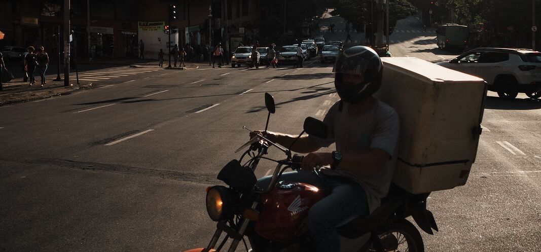 Ein Lieferant auf einem Motorrad mit einem Paket auf einer Kreuzung. Lieferdienste boomen in Brasilien.