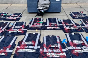 Erinnerung an die getöteten Journalist*innen in Gaza: Pressewesten mit Blut liegen auf dem Boden.