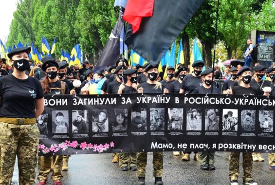 Viele Frauen demonstrieren in Uniform und mit ukrainischen Flaggen, sie halten ein schwarzes Banner, auf dem Fotos getöteter Soldatinnen zu sehen sind.