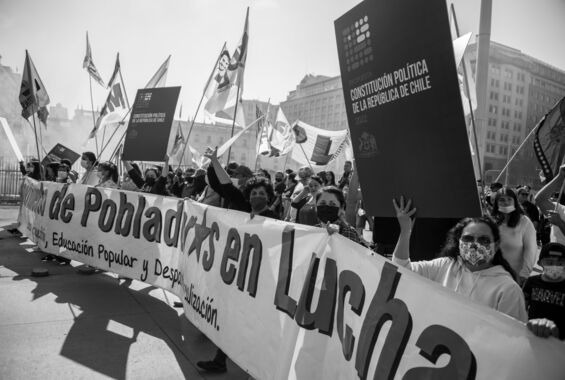 Ein Protest der Anhänger*innen des neuen Verfassungsentwurfs in Santiago, Chile. Menschen mit Fahnen und Schildern hinter einem langen Transparent sind zu sehen.