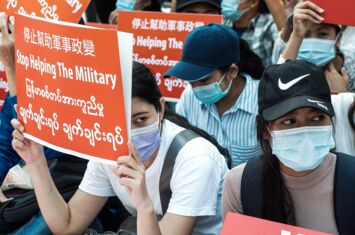 Frauen halten Protestschilder hoch mit der Aufschrift "Stop Helping the Military"