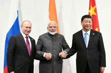 Narendra Modi in der Mitte hält Wladimir Putin (links) und Xi Jingping (rechts) an der Hand, im Hintergrund die Landesflaggen