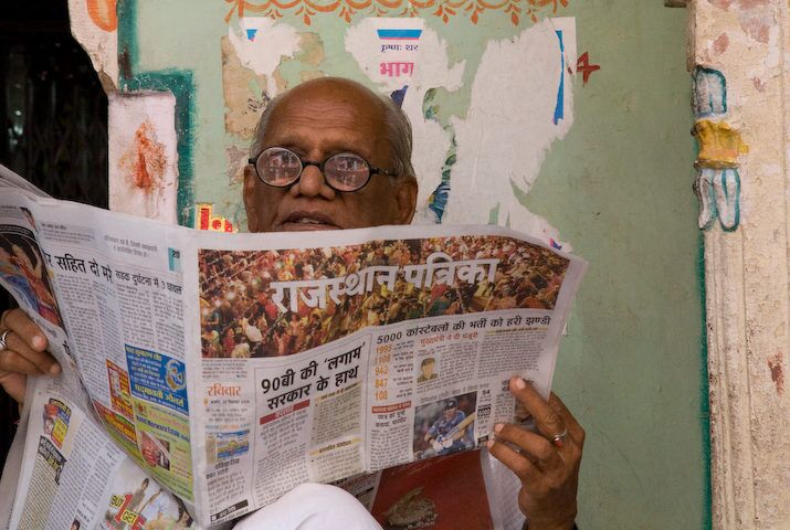 Ein Mann mit Brille liest eine Zeitung