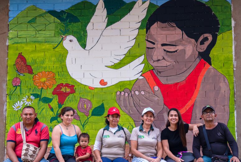 Wand Graffiti mit ehemaligen FARC-Kämpferinnen, die vor dem Wandgemälde sitzen