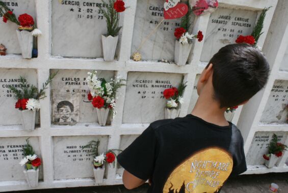 Kind schaut auf Urnengräber geschmückt mit Blumen. 50 Jahre Putsch in Chile.