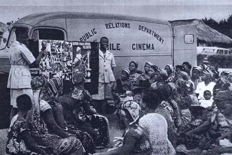 Afrikanisches Kino legitimierte lange den Kolonialismus. Das Bild zeigt einen Wagen als mobiles Kino mit einigen Zuschauer*inne davor.