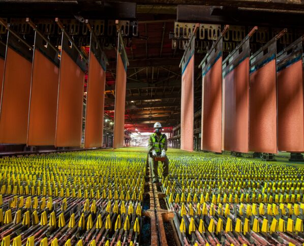 Kupferplatten in einer Produktionshalle in Chile, ein Arbeiter mit Helm und Schutzmaske in der Mitte