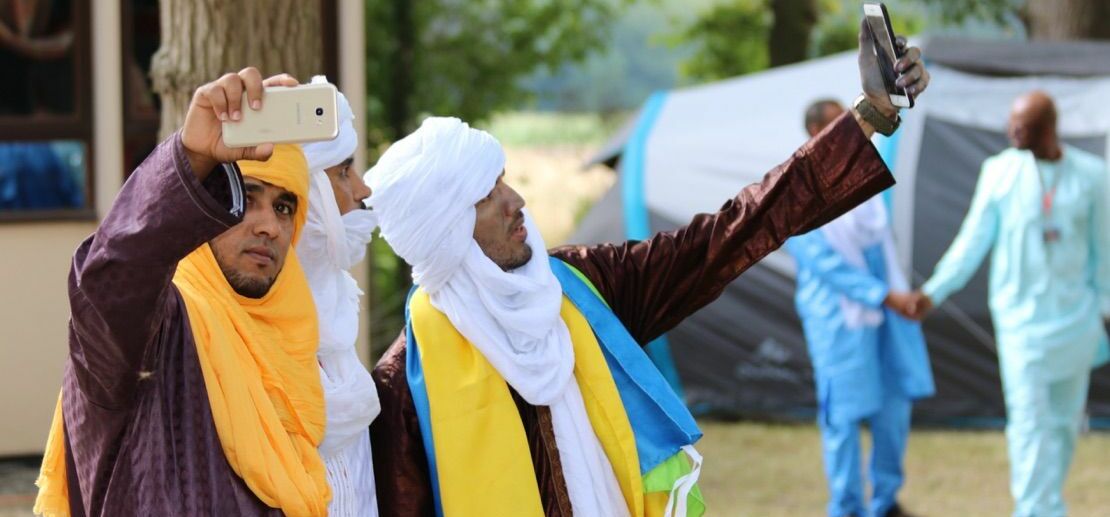 Drei Personen mit Handys beim Jahrestreffen der Tuareg-Diaspora in Frankreich