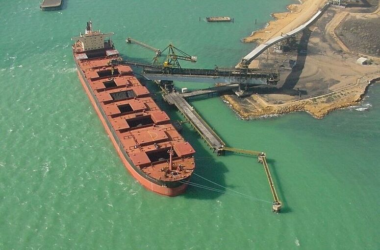 Blick auf ein Frachtschiff im Hafen von Puerto Bolivar in Kolummbien beim Verladen von Kohle (vogelperspektive)
