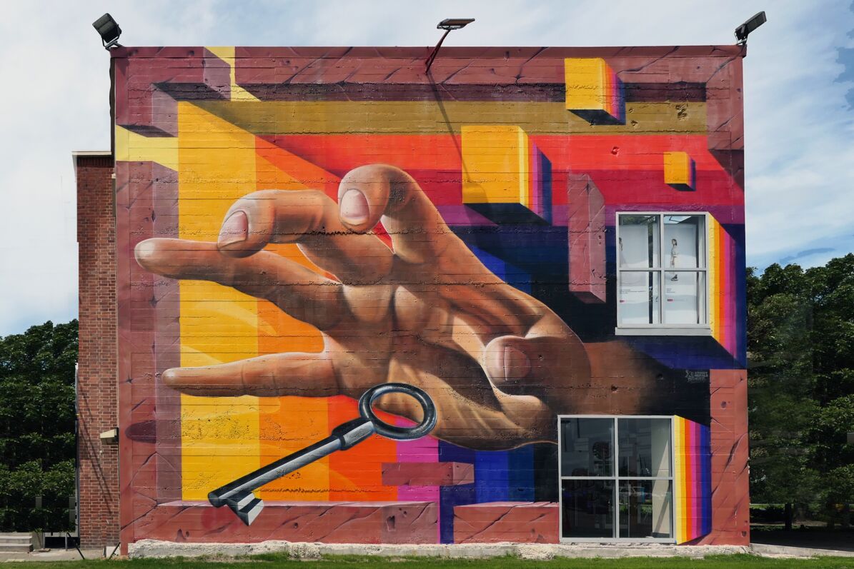 Wohnen und Eigentum: Ein buntes Wandbild zeigt eine große Hand die nach einem Schlüssel greift