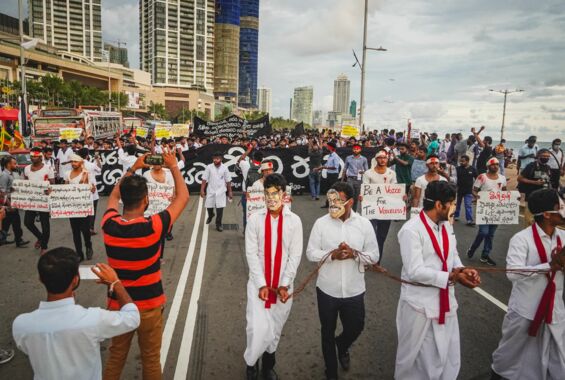 Protestierende mit Schildern, Bannern und Masken auf einer breiten Straße in Colombo, Sri Lanka