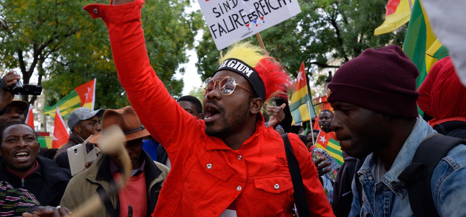 Szene eines Straßenprotests gegen Faure Gnassingbé in Belgien. Die Menschen schwingen togoische Fahnen und Schilder
