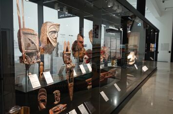 Eine große Museumsvitrine entgält eng gestellt Masken und Kulturgegenstände aus Ozeanien
