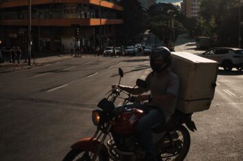 Ein Lieferant auf einem Motorrad mit einem Paket auf einer Kreuzung. Lieferdienste boomen in Brasilien.
