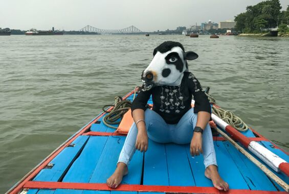 Person mit einer Maske einer heiligen Kuh auf einem Boot