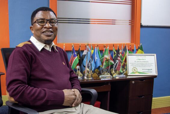 Portrait von Mithika Mwenda (Direktor der Panafrican Climate Justice Alliance) in seinem Büro mit Zertifikat für die 100 wichtigsten Persönlichkeitenn