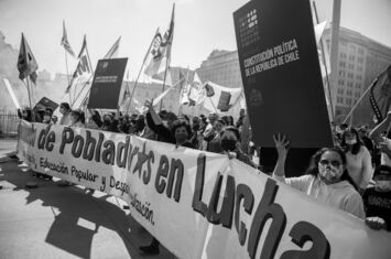 Ein Protest der Anhänger*innen des neuen Verfassungsentwurfs in Santiago, Chile. Menschen mit Fahnen und Schildern hinter einem langen Transparent sind zu sehen.