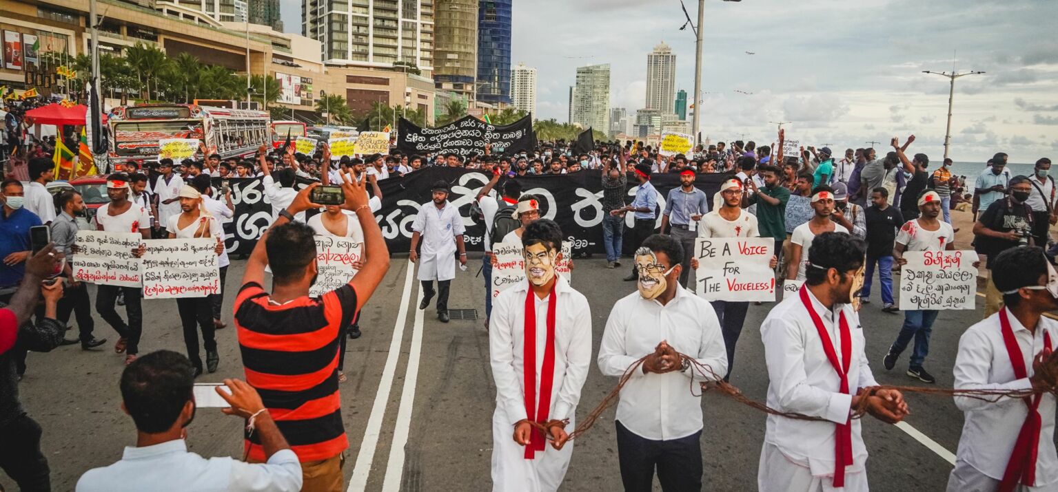 Protestierende mit Schildern, Bannern und Masken auf einer breiten Straße in Colombo, Sri Lanka