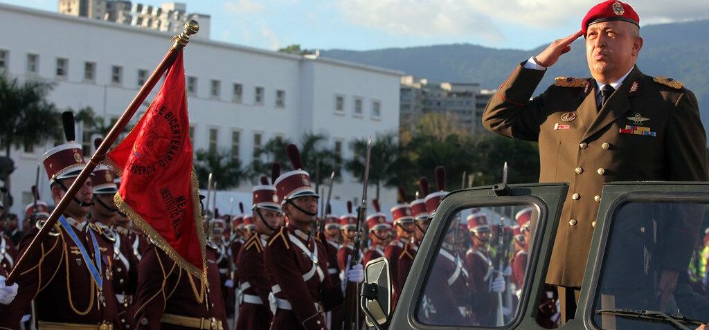 Präsident Hugo Chávez bei einer Militärparade, in Uniform auf einem Militärwagen, vorbeifahrend an Soldaten