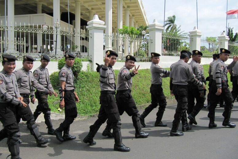 Korrupte Institution: Eine Gruppe junger indonesischer Polizeibeamten, an der Kamera vorbeilaufend.