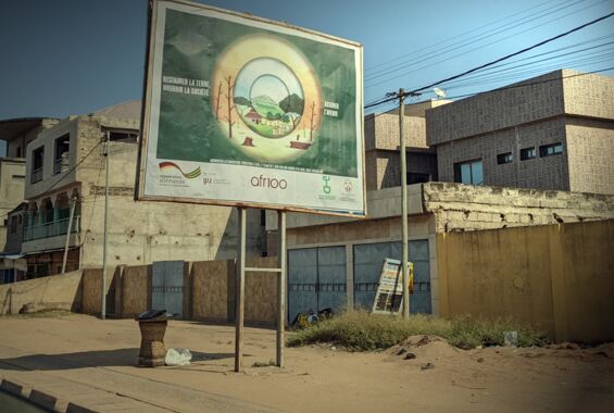 Auf einer Straße große Werbetagel für Aufforstungsaktivitäten in Togo