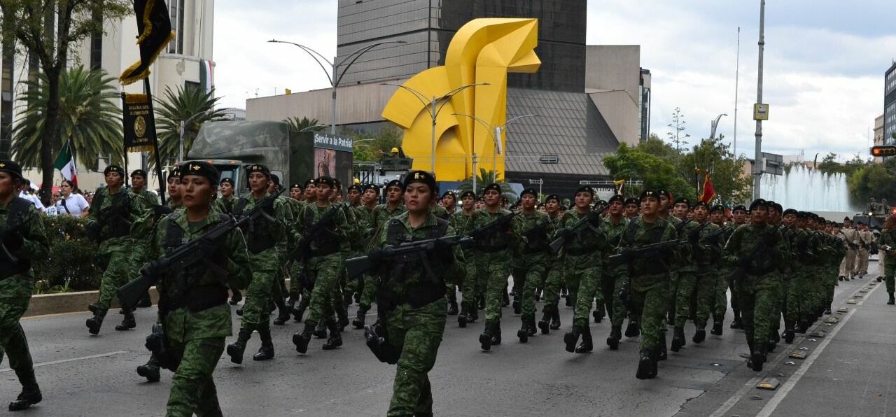 Soldatinnen marschieren in Uniform und mit Waffe in Reihen durch die Straßen von Mexiko City