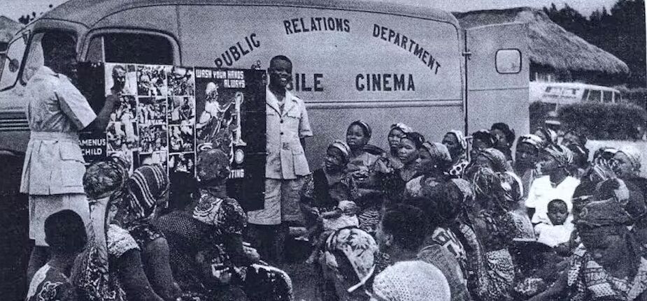 Afrikanisches Kino legitimierte lange den Kolonialismus. Das Bild zeigt einen Wagen als mobiles Kino mit einigen Zuschauer*inne davor.